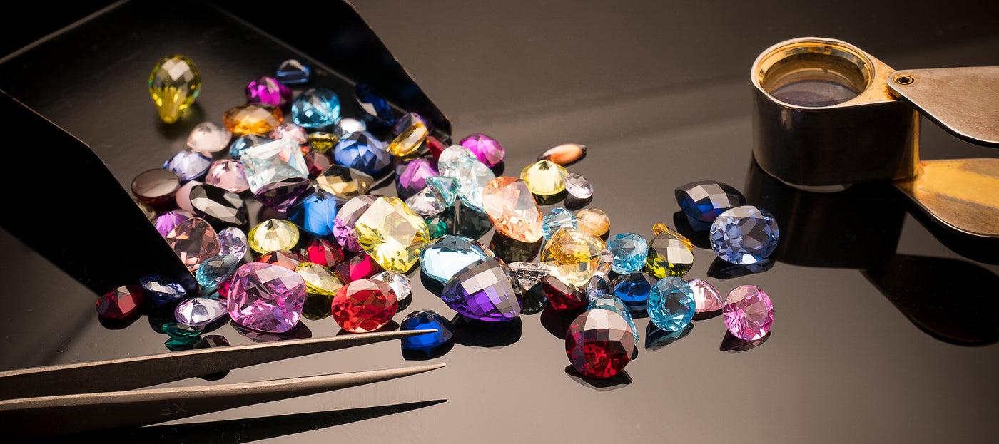 Loose natural gemstones with gem tools – sapphire, ruby, emerald and more on jeweler’s display