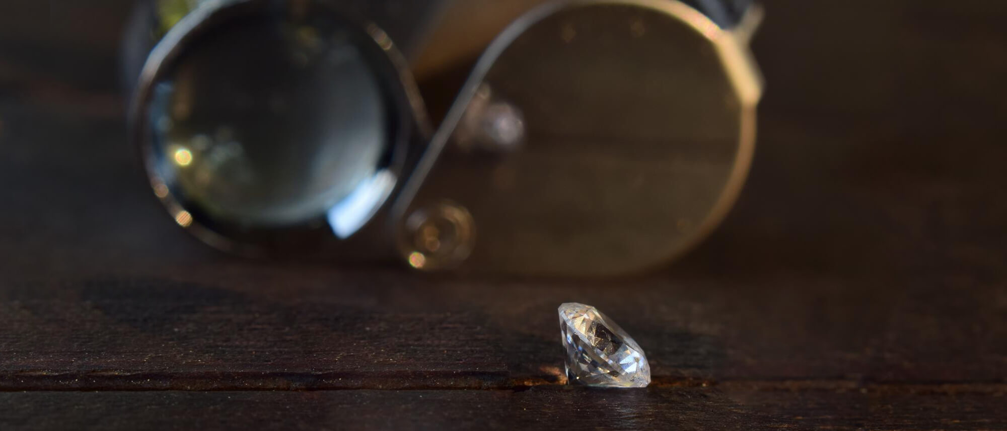 White gemstone on table with gemological loupe 