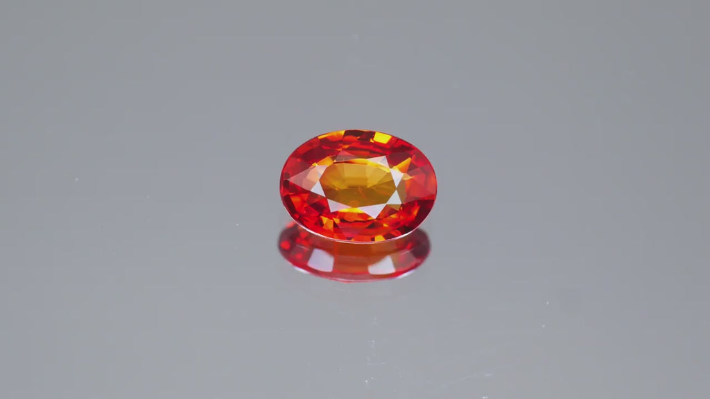 Natural orange sapphire gemstone, 0.87 carats, oval cut, fire orange red color, VVS clarity, Madagascar origin, beryllium treated, seller's certificate