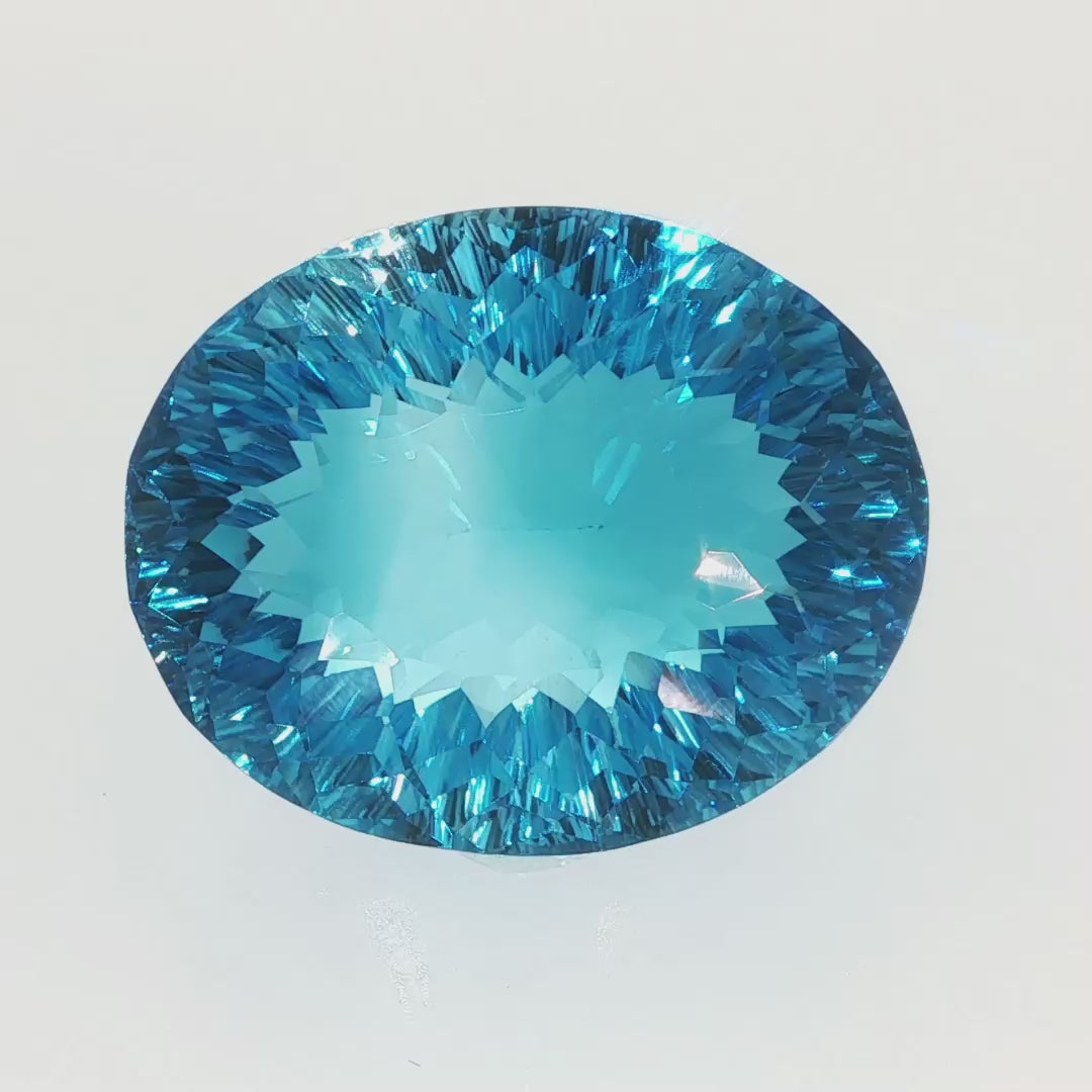 Natural Swiss Blue Topaz, 63.27 carats, oval concave cut, eye-clean clarity, vivid Swiss blue color, transparent gemstone